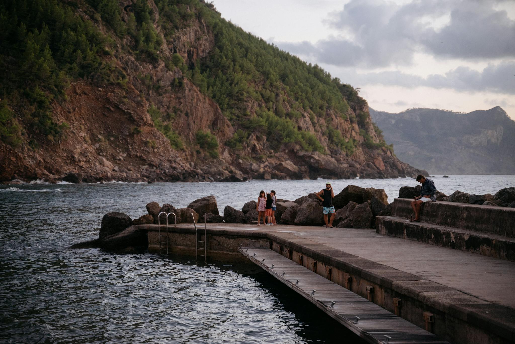 A couple sitting on a pier near the water