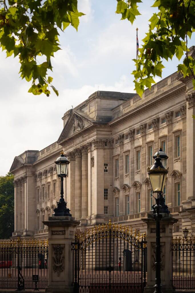 Majestic view of Buckingham Palace, a famous landmark in London, surrounded by ornate gates and lush greenery.