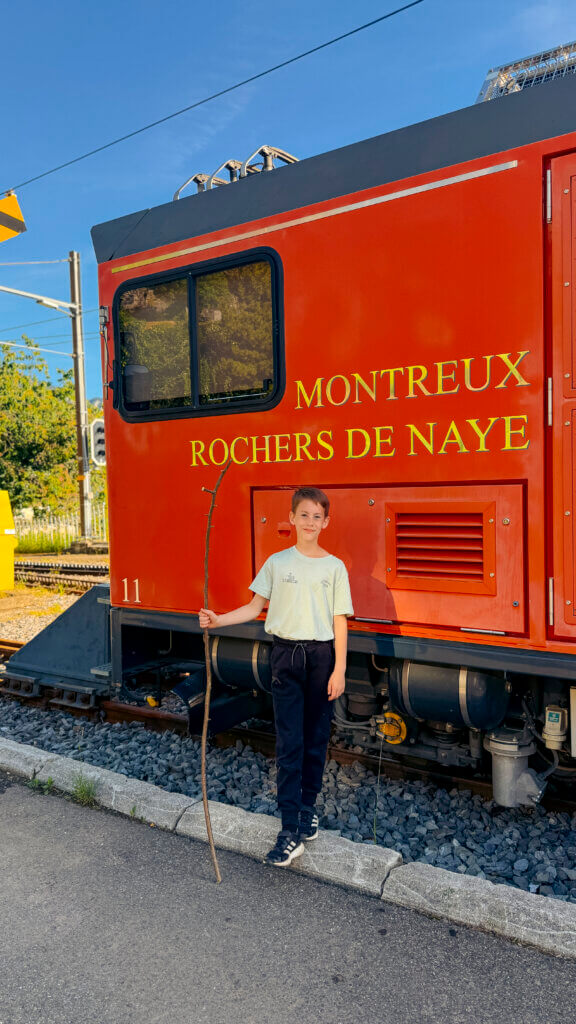 A boy stands next to the vintage cogwheel train to Rochers-de-Naye in Montreux, Switzerland